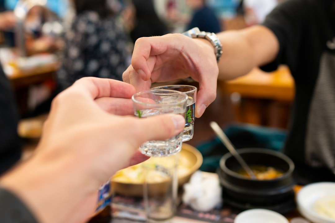 맑은 유리잔에 담긴 물을 마시는 사람의 모습, 충분한 수분 섭취의 중요성을 나타냅니다.